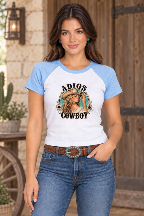Styled mockup of the Adios Baby T-Shirt in white and baby blue, worn by a brunette with denim and an open turquoise-stone belt buckle.
