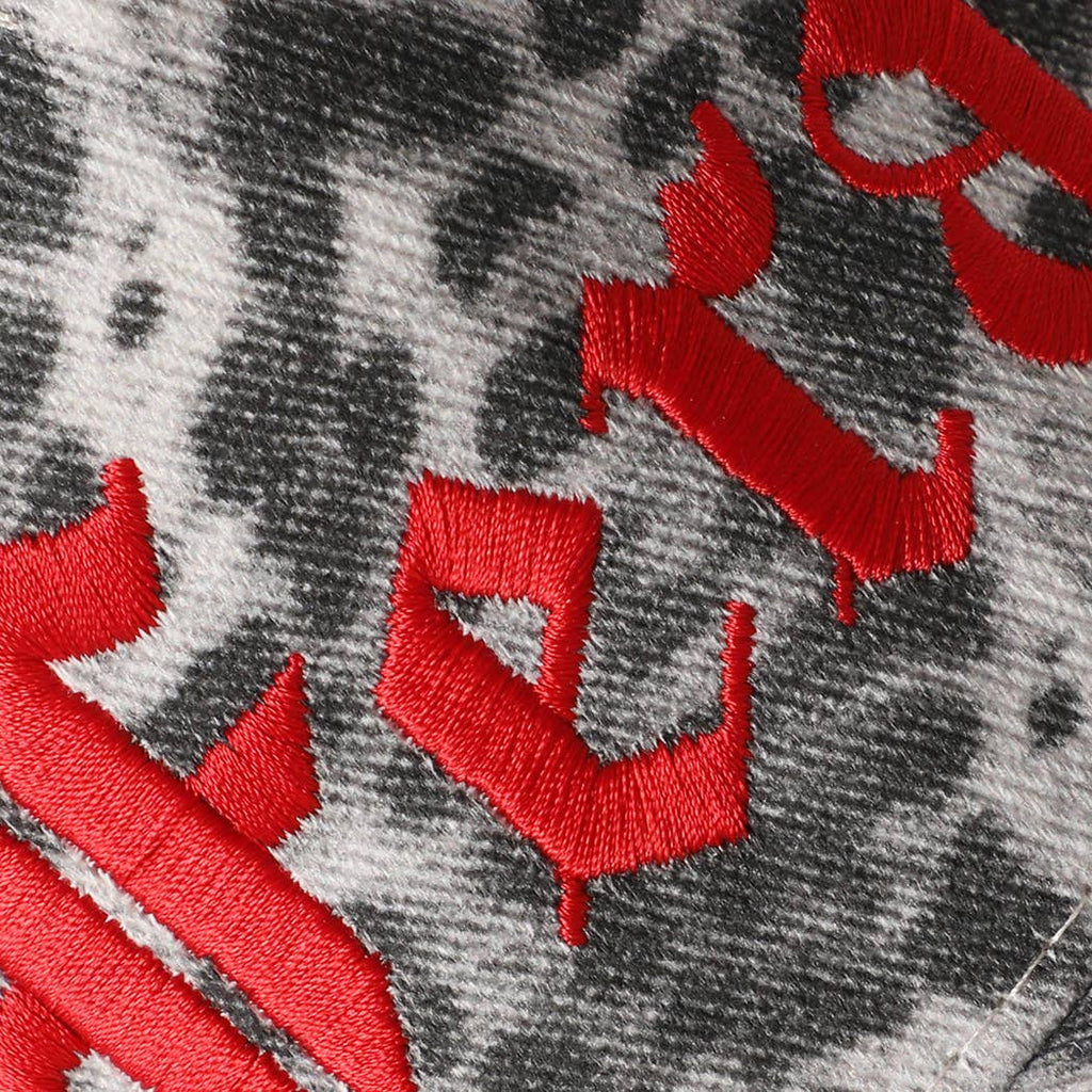 Close-up of the red Feral embroidery on grey leopard print cotton