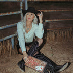 Model styling the Vegas leather clutch wristlet with western boots