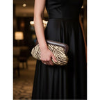 Supplier styling photo showing the brown zebra clutch held in one hand; clutch only.